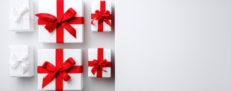 An overhead view displays several wrapped gift boxes with red ribbons against a neutral white background. The boxes present a clean, bright aesthetic, ideal for various design projects. The composition suggests potential use for promotional material, holiday themes, or general visual interest, suitable for commercial applications.の素材