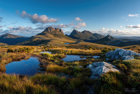 This landscape image captures a mountain range with several small lakes and green vegetation under a blue sky with clouds. The scene displays a natural outdoor environment. The photograph's style uses natural lighting and color gradients, and is potentially suitable for editorial content and commercial use.の素材