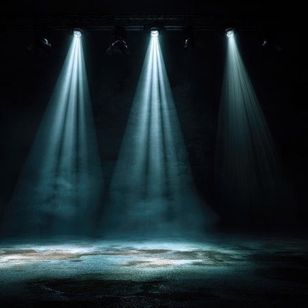 Three bright spotlights shine downwards, creating beams of light in a darkened setting. The beams highlight a textured, possibly wet, surface with a hazy effect. The composition is centered, emphasizing the light against the shadows. This image could be used for various creative projects or visual storytelling.の素材