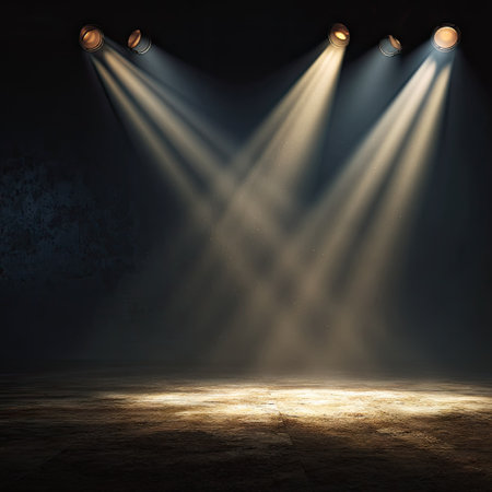 Powerful spotlights cast bright beams of light across an empty stage, creating a dramatic atmosphere. The scene features a dark background, contrasted by the warm glow of the light. The composition highlights the use of light and shadow, with potential uses in advertising or editorial design.の素材