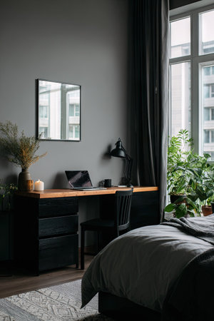 This image showcases a modern bedroom with a desk, laptop, and a large window. The scene is illuminated by natural light, highlighting the textures of the wall, desk, and bed linens. It could be used for various purposes, including interior design projects or as a backdrop for digital content.の素材