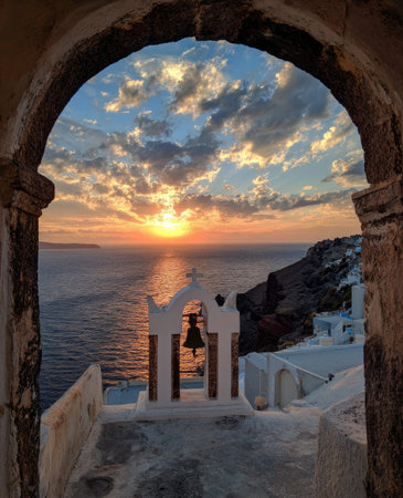 An archway frames a stunning ocean sunset, illuminating a bell tower in the foreground. The image displays a vibrant sky with cloud formations, and the warm colors of the setting sun. This landscape shot may be suitable for travel, tourism or editorial use, with copy space available.の素材
