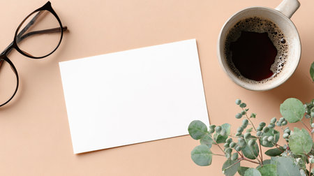 A top-down composition showcases a coffee cup, blank card, eyeglasses, and greenery on a neutral-toned surface. The image exhibits a clean aesthetic with muted colors and soft lighting, creating a calm and inviting atmosphere. Suitable for use in lifestyle or business-related content, offering ample copy space.の素材