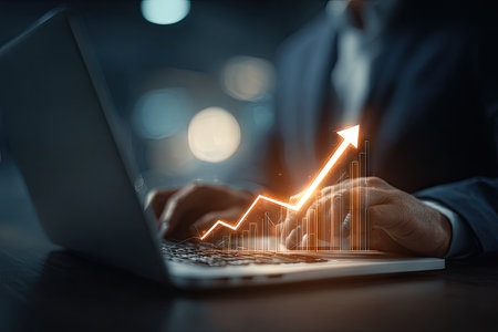 A person is using a laptop with a digital arrow overlayed. The scene features shallow depth of field, with soft lighting and a blurred background. The image depicts a business context, suggestive of financial growth and data analysis. Ideal for illustrating concepts in business, technology, and economic reports.の素材