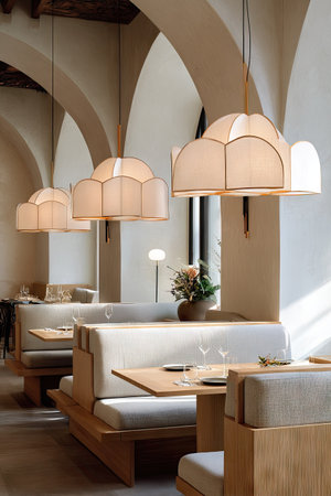 An interior photograph showcases a dining area with arched architecture. Beige booths with wooden tables are arranged beneath decorative pendant lights. The composition is well-lit, highlighting textures and shapes. This image is suitable for various commercial uses, including advertising and editorial content related to design or hospitality.の素材