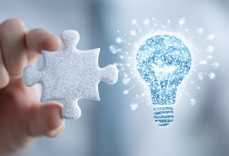 A hand holds a puzzle piece next to a lightbulb rendered with digital particles. The image uses a shallow depth of field, with soft focus on the subjects against a blurred background of varying shades of blue. It conveys concepts like innovation, problem-solving, and technology. Suitable for educational or business contexts.の素材