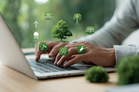 A person's hands typing on a laptop keyboard are visible, accompanied by several green icons floating above, indicating environmental themes. The image features a bright, natural daylight setting, the color palette includes greens and soft tones suggesting growth and eco-consciousness. Suitable for use in articles discussing innovation, or environmental concerns.の素材