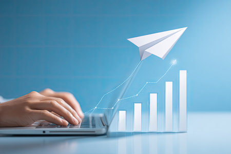 A close-up view shows hands typing on a laptop with a paper airplane and growth chart overlayed on a blue background. The composition uses soft lighting and a blurred effect, suggesting data-driven business concepts. Ideal for illustrating innovation, communication, and financial success. Suitable for diverse commercial and editorial applications.の素材