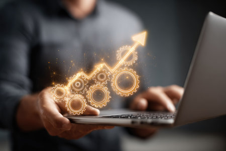 A person is shown working on a laptop, with an overlaid graphic of gears and an upward arrow. The visual elements suggest growth and progress in a business setting. The image uses a shallow depth of field, with soft lighting and a modern style, suitable for various commercial or editorial applications.の素材