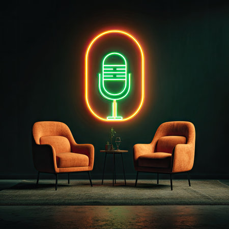 Two orange armchairs face each other below a glowing neon microphone sign, suggesting a podcast recording setup. The composition uses a dark, minimalist aesthetic with a focus on lighting. The interior setting has a modern feel. This image suits various commercial applications such as advertising and editorial content.の素材