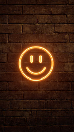 An illuminated neon smiley face is presented against a textured brick wall. The image features a vibrant orange glow against the darker brick, creating a contrast. The composition is straightforward, emphasizing the simplicity of the subject. Suitable for advertising and editorial purposes related to positivity.の素材