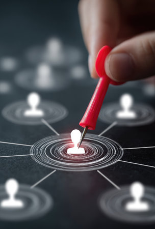 A close-up view presents a hand positioning a red pin on a glowing person icon surrounded by other similar icons. The background is a dark tone, and the lighting is soft. The image suggests a concept of targeting specific individuals within a larger network. It can be used for various commercial or editorial applications.の素材