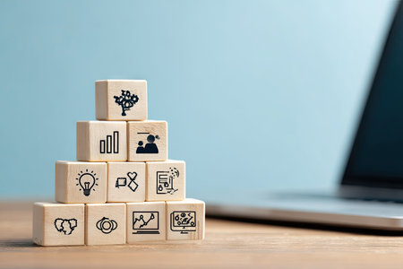 A close-up captures wooden blocks arranged in a pyramid formation, each bearing a different icon. The blocks sit on a wooden surface against a blurred background. The composition suggests concepts of business, innovation, and digital technology. Suitable for projects related to communication, education, or online presence.の素材
