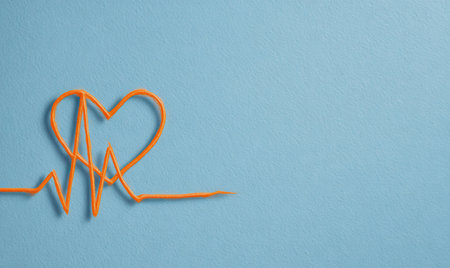 An overhead view displays an orange wire forming a heart and a heartbeat waveform against a solid blue backdrop. The image utilizes a minimalist style with clean lines and contrasting colors, providing a simple yet striking visual. It may be suitable for projects related to health, wellness, or design.の素材