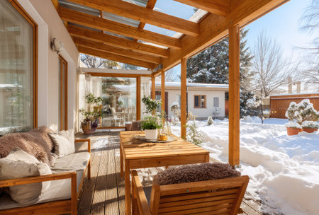 This image showcases a wooden patio featuring tables and chairs, covered with snow, suggesting a winter season. The composition highlights natural lighting from the exterior, reflecting off the snowy terrain. Ideal for commercial applications, it can be used to represent seasonal themes or outdoor lifestyles.の素材