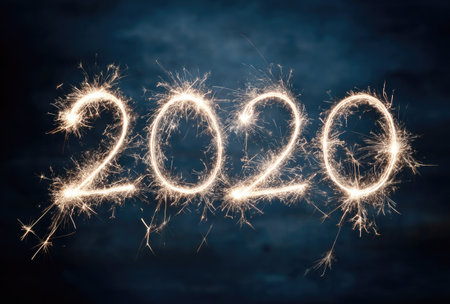 The image features the number 2020 crafted with bright, shimmering sparklers, set against a dark, contrasting backdrop. The visual characteristics include glowing, golden light and a blurred, festive composition. The image's clean presentation suggests use in promotional materials or editorial content related to celebrations or events.の素材