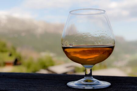 Glass with cognac, whiskey or brandy in front of idyllic landscape.の写真素材