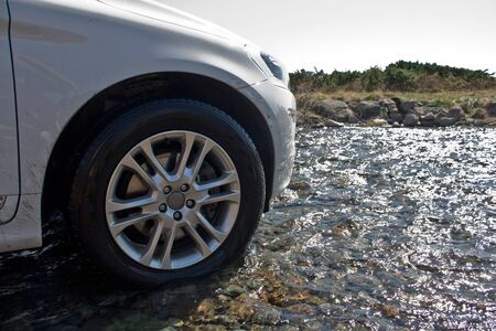 White off-road vehicle drives over water of a river in the mountains of Norway.の写真素材