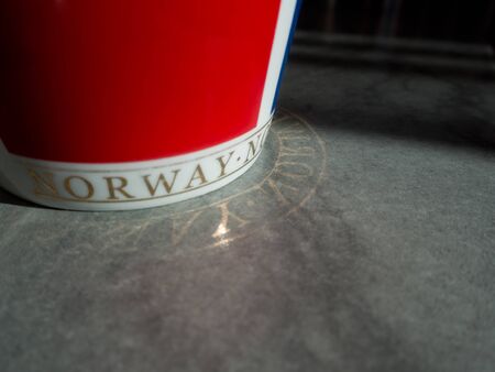 Red cup with Norwegian text reflected on the floor.の写真素材