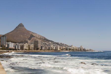 Mountains, hotels and deep blue water with waves at the Sea Point, beach promenade in Cape Town South Africa.の写真素材