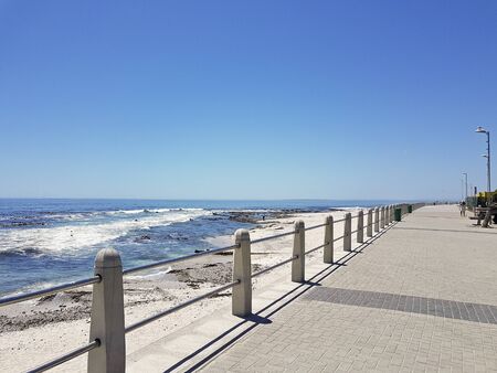 Mountains, hotels and deep blue water with waves at the Sea Point, beach promenade in Cape Town...