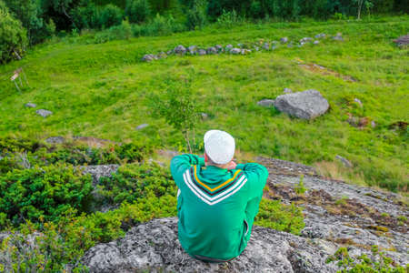 Young man sits and looks at the Norwegian landscape from above. Norway.の写真素材