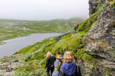 Hikers on the Hydnefossen waterfall and Hydna river on VeslehÃ¸dn Veslehorn mountain in Hemsedal,...