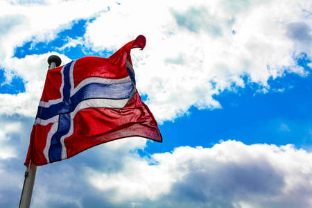 The national flag of Norway in the rough wind and blue sky with clouds.の写真素材
