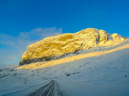 Driving at sunrise through mountains and forests in Norway. Sunshine on a mountain top.の写真素材
