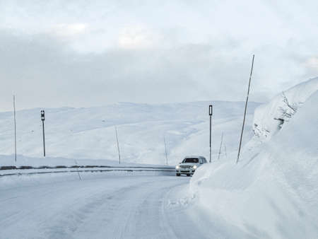 Driving through snowy white road and landscape in Norway. Car in front.の写真素材