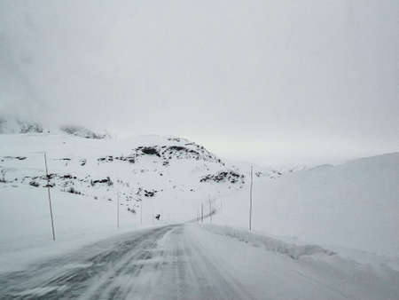 Driving through snowy white road and landscape in Norway.