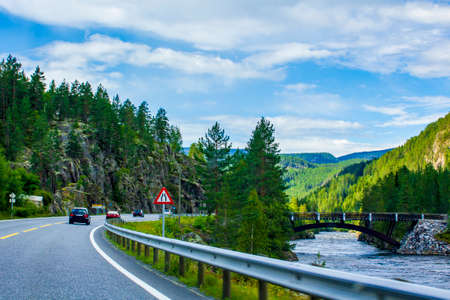Driving through Norway in summer with a view of the mountains and the fjord.