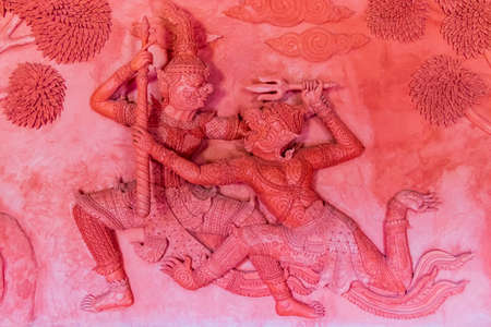 Fighting wall figures sculptures Wat Sila Ngu with the red temple Wat Ratchathammaram on Koh Samui...