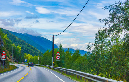 Driving through Norway in summer with a view of the mountains and forests.