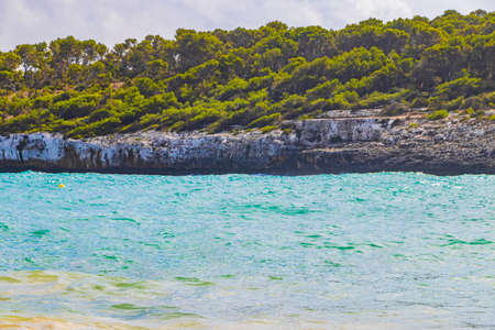 Turquoise beach and cliffs ses Fonts de n'AlÃ­s in bay CalÃ³ d'en Garrot Mallorca Spain.の写真素材