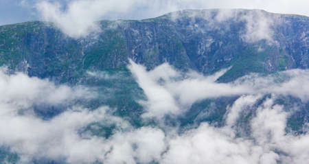 Fog mist clouds rain and cliffs on mountain in norwegian landscape Jotunheimen National Park Norway.