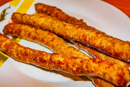 Thin crispy grilled sausage on a white plate background.の写真素材