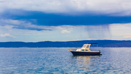 Huge rain clouds and showers in the background of a boat in Novi Vinodolski Croatia.の写真素材