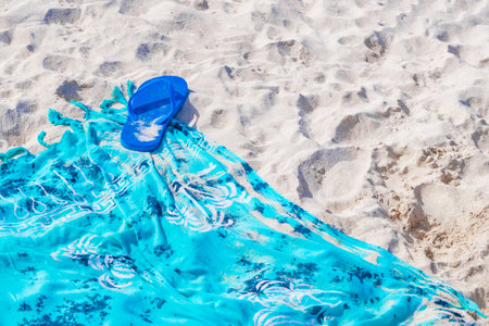 Blue flip-flops on blue beach blanket or towel on white sand in Playa del Carmen Mexico.の写真素材