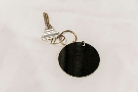 Hotel room key with round black blank pendant and white background.