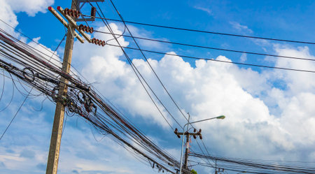 Absolute cable chaos on Thai power pole in Sakhu Thalang Phuket Thailand with blue sky.の写真素材
