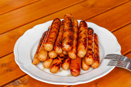Grilled sausages on a white plate and wooden table barbecue season has started.の写真素材