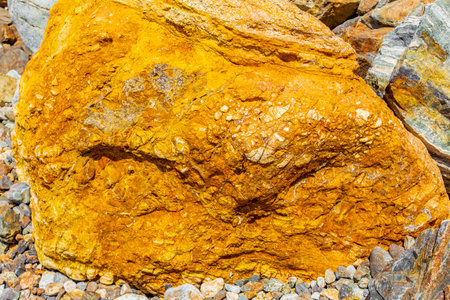 Beautiful golden orange or yellow colored boulders and rocks on the coast of Kos Island in Greece.の写真素材