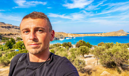 Russian tourist traveler at Lindos Beach bay panorama view with turquoise clear water boats tourists and sun on Rhodes Greece.の写真素材