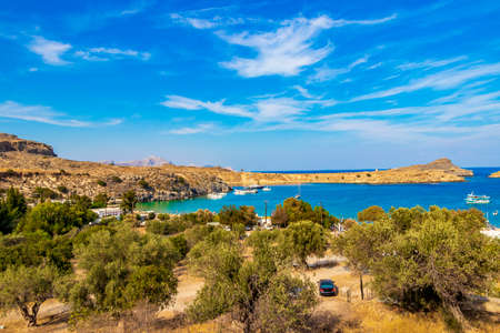 Lindos Beach bay panorama view with turquoise clear water boats tourists and sun on Rhodes Greece.の写真素材