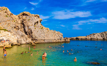 St Pauls Bay Lindos beach panorama view with turquoise clear water boats tourists and sun on Rhodes Greece.のeditorial素材