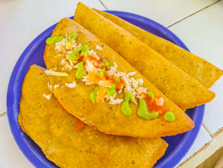 Mexican empanada with cabbage and hot sauce on blue plate white background from Playa del Carmen in Mexico.の写真素材