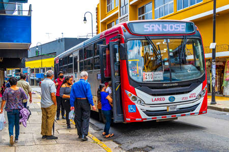San JosÃ© Costa Rica January 04, 2021 Colorful bus busses in busy traffic and cityscape with stores people and cars in San JosÃ© Costa Rica.のeditorial素材
