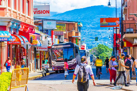San JosÃ© Costa Rica January 04, 2021 Colorful bus busses in busy traffic and cityscape with stores people and cars in San JosÃ© Costa Rica.のeditorial素材