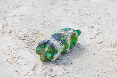 Plastic bottle stranded washed up garbage waste and trash pollution on the Botafogo Beach sand in...